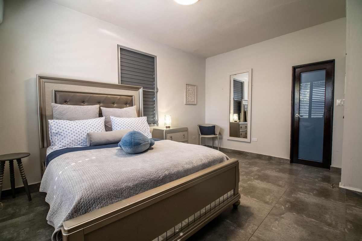 King bedroom with grey headboard and coastal linens