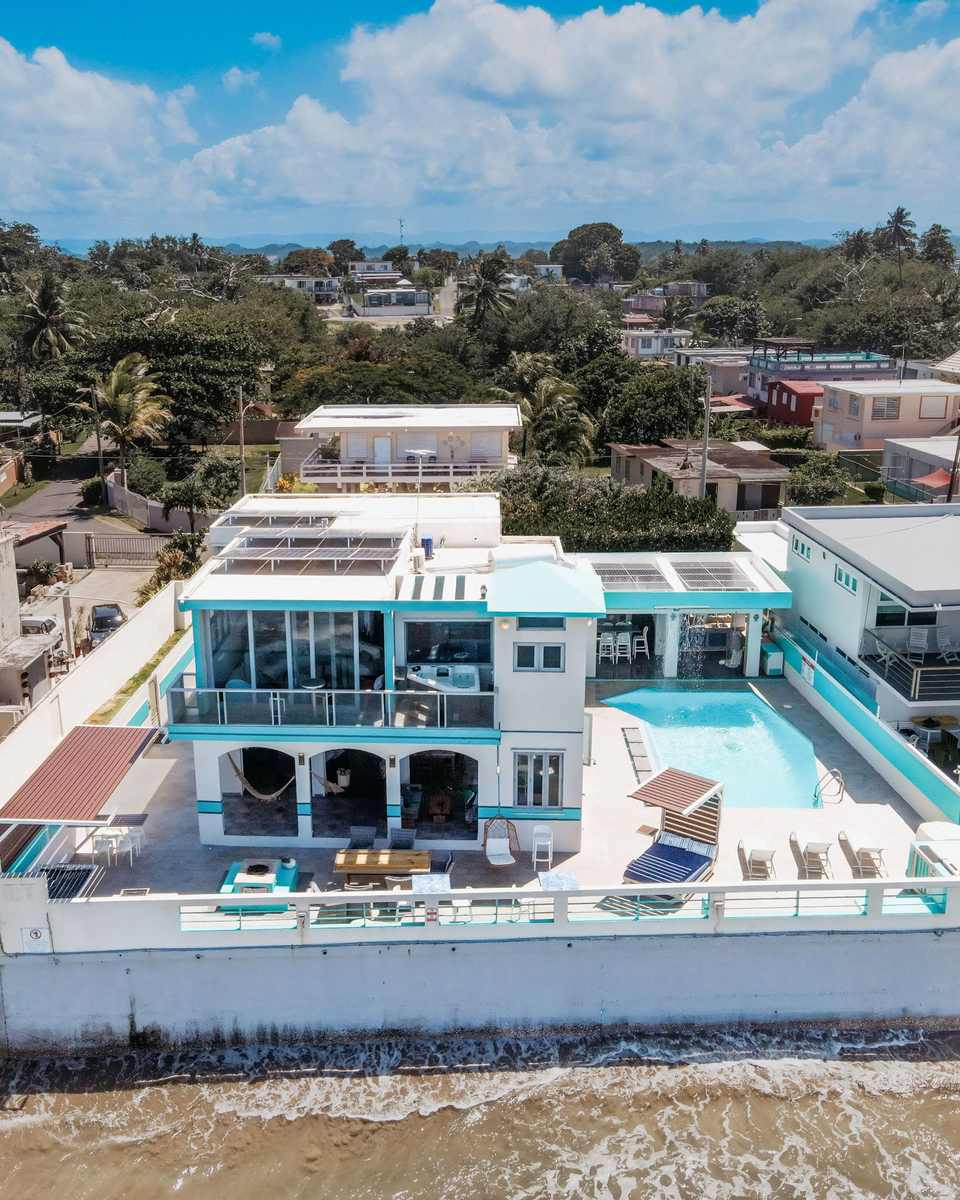 Aerial view of the white beach house with pool terrace beside the ocean