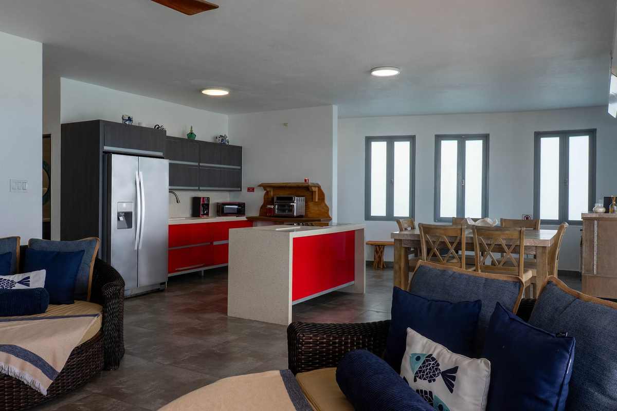 Full kitchen in red and white with stainless appliances and bar seating