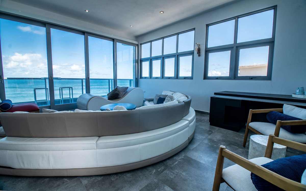 Curved white lounge sofa in front of panoramic ocean-view windows